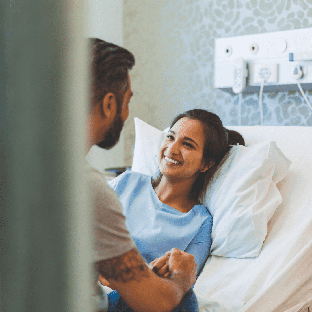 Patient smiling in bed with her partner
